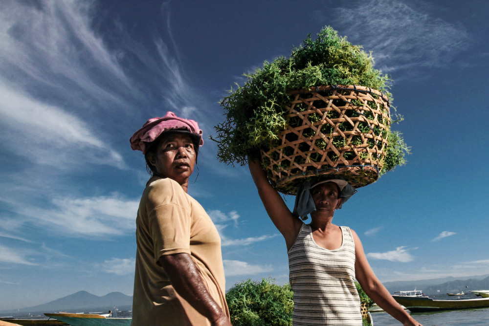 Putting a loaded basket on the head is not easy, another person is there to help.