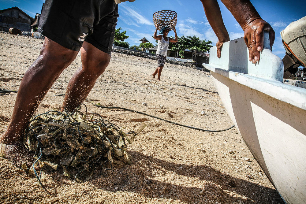 A woman moves her feet back and forth on the lines which are crubbed in the sand and cleaned for reuse.